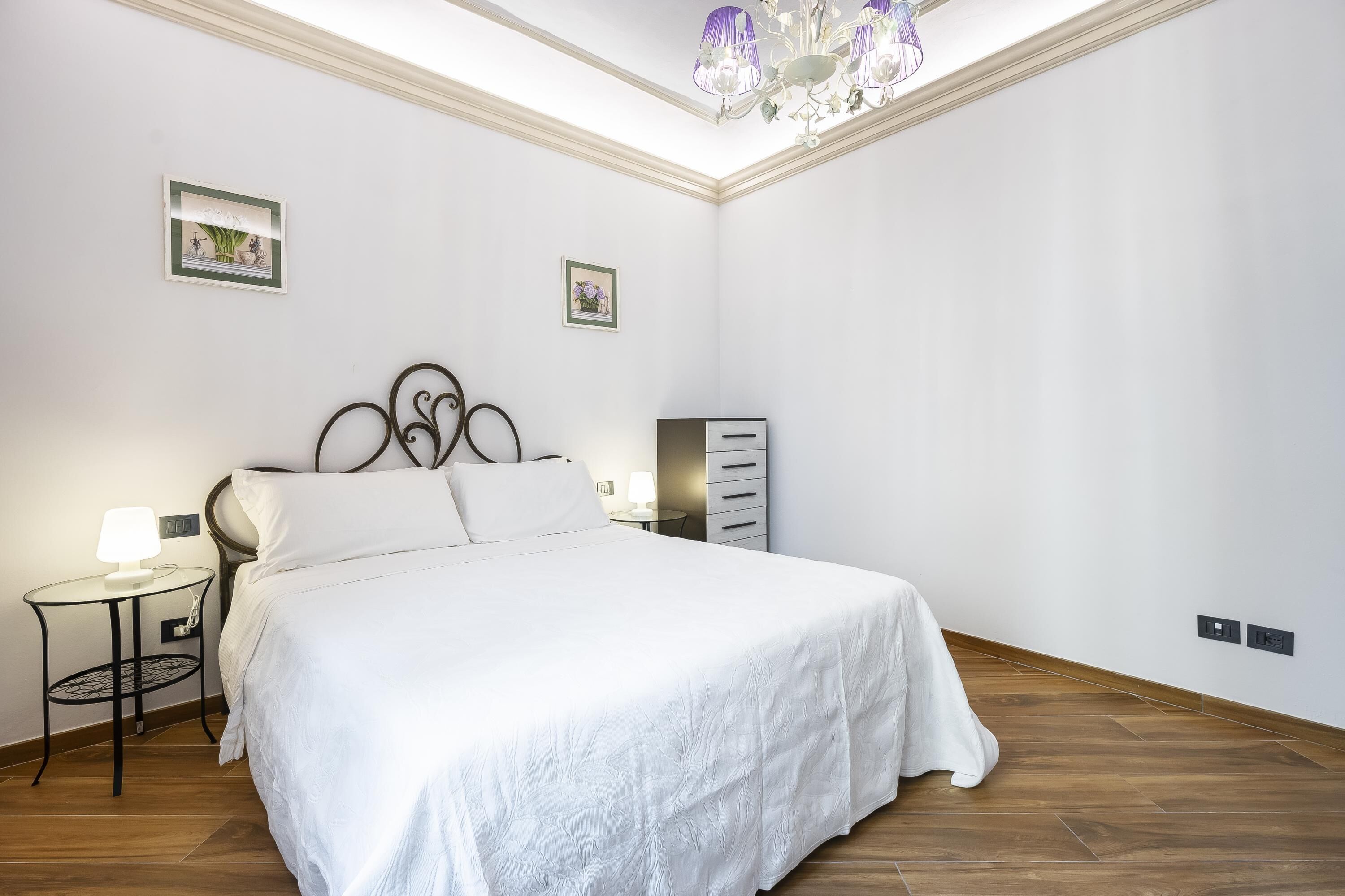 Ein Schlafzimmer mit Bett, Nachttisch, Kommode und einer Deckenleuchte.