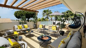 A sunlit outdoor patio with wicker furniture, a swing chair, and a view of the sea. - Praia by Check-in Portugal (Albufeira)