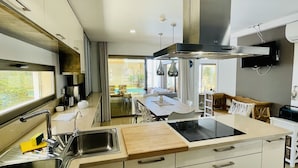 A modern kitchen with a large island, stainless steel appliances, and a view of the outdoor dining area. - Praia by Check-in Portugal (Albufeira)