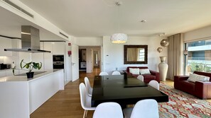 A modern kitchen with white cabinetry, a central island, and a dining area with a black table and white chairs.