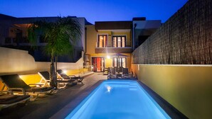Ein Swimmingpool mit Liegestühlen, einer Palme und einem Gebäude mit Balkon.