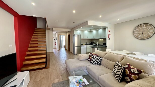 Eine moderne Wohnung mit Treppe, Wohnzimmer, Küche und Essbereich.