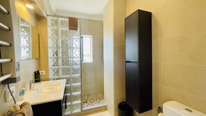 Une salle de bain moderne avec une douche à l’italienne en verre, un lavabo blanc et un meuble noir.