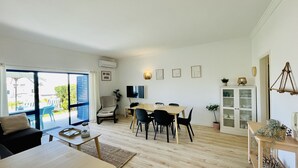 Ett modernt vardagsrum med en matplats, en soffa, ett soffbord och en tv.
