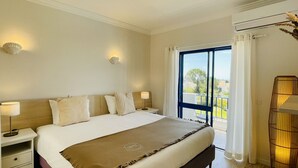 Ett hotellrum med en stor säng, två sängbord, ett fönster med gardiner och en luftkonditioneringsanläggning.