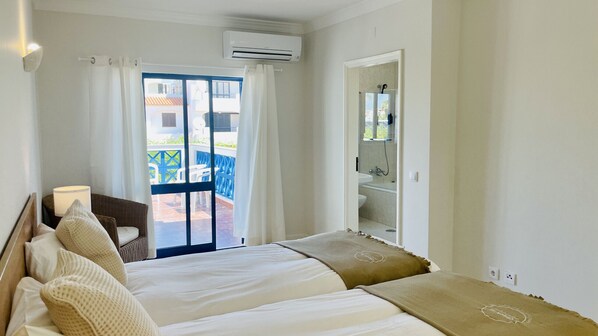 A hotel room with a bed, a desk, and a bathroom with a shower.