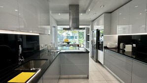 Cozinha moderna com ilha central, eletrodomésticos de aço inoxidável e vista para área externa.