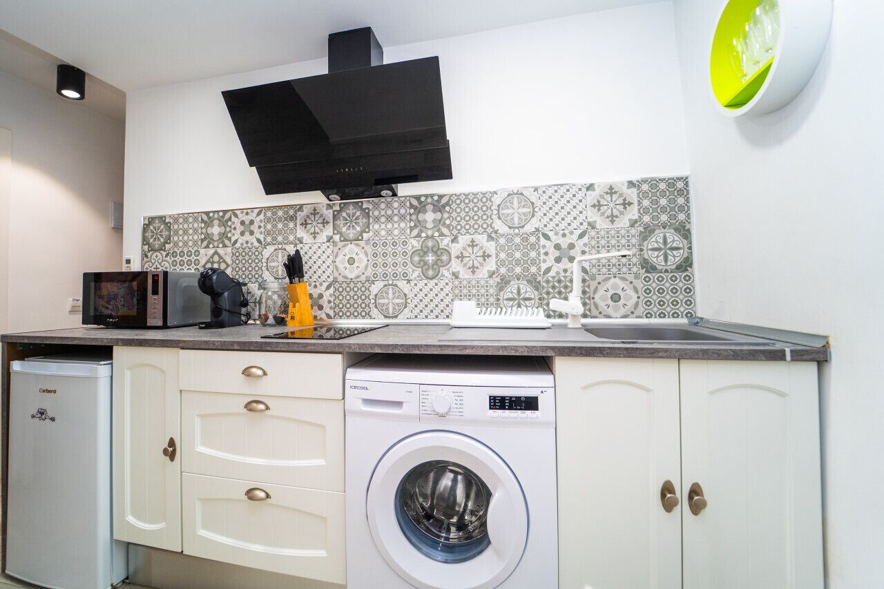 Een kleine keuken met een wasmachine, een magnetron en een broodrooster.
