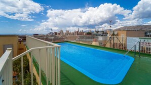 Une piscine sur le toit offrant une vue dégagée sur les gratte-ciel de la ville et les montagnes en arrière-plan.