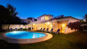 Ein zweistöckiges Haus mit Swimmingpool, Sitzgelegenheiten im Freien und einem gepflegten Rasen.
