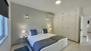A bedroom with a bed, bedside tables, a wardrobe, and an air conditioning unit. - Nicola by Check-in Portugal (Albufeira)