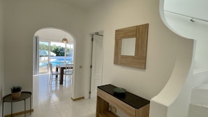A hallway with a view to a pool area, a door, a wooden console table, and a framed mirror. - Nicola by Check-in Portugal (Albufeira)