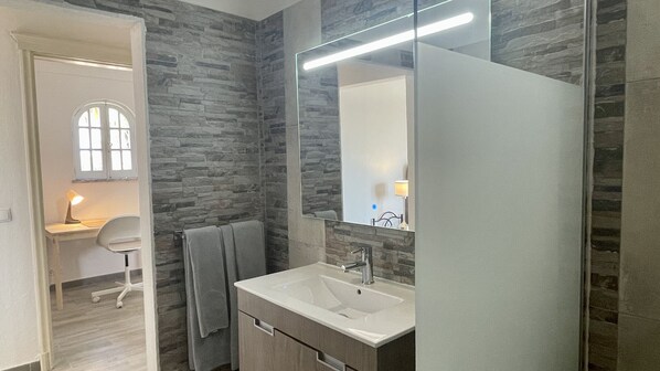 A bathroom with a stone wall, a white sink, and a mirror.