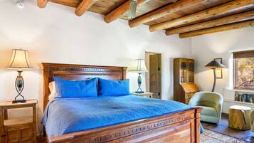 A bedroom with a wooden bed, two bedside lamps, a wooden cabinet, a chair, and a window with a view.