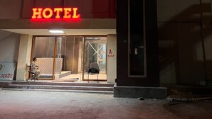 Ett hotell med en tydlig skylt som visar ordet ”HOTEL”, en skylt som visar ”HOTEL PATEL STADIUM” och en skylt som anger ”ETT KVARTER”.