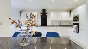 A modern kitchen with white cabinets, a black range hood, and a microwave. - Cosy and Luxurious House for 10 Guests in Darwen (Darwen)