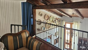 A wooden-beamed ceiling, a striped sofa, and a wall with decorative plates.