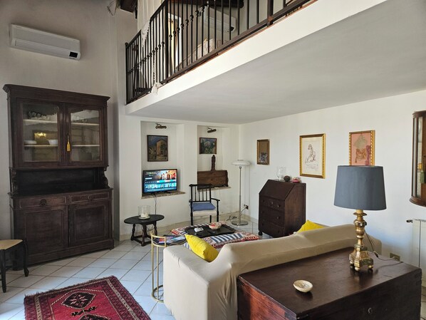 Una sala de estar con sofá, televisión, mueble y lámpara.