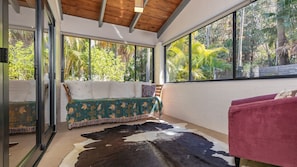 Ein Zimmer mit Glastür zu einem Balkon, einem Bett mit gemustertem Überwurf und einem Kuhfellteppich auf dem Boden.