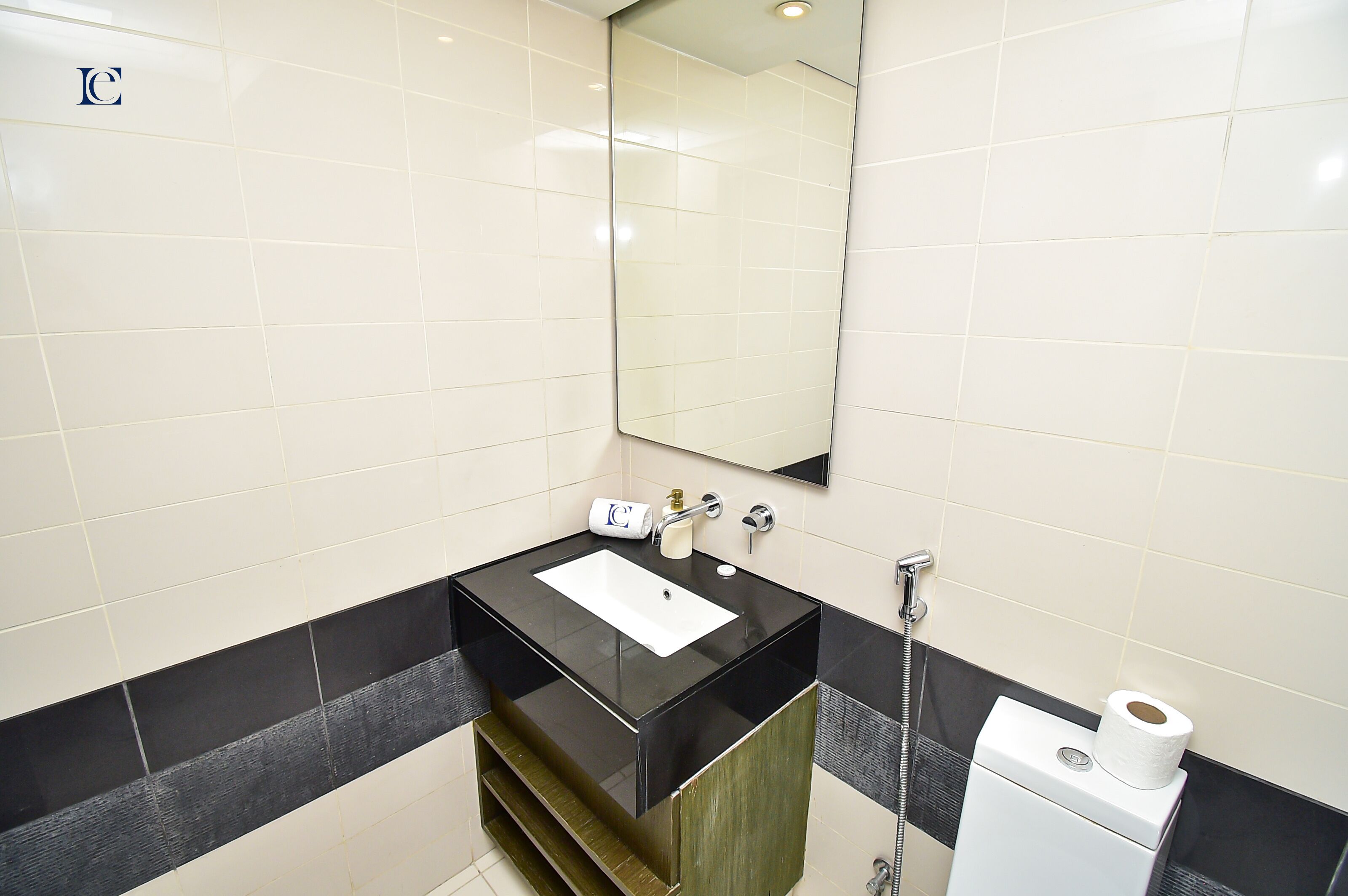 A modern bathroom with a black sink, white tiles, a mirror, and a toilet.