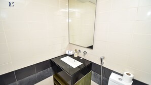 A modern bathroom with a black sink, white tiles, a mirror, and a toilet. - New 1BR Apt - Burj Khalifa View - LOFT (Dubai)