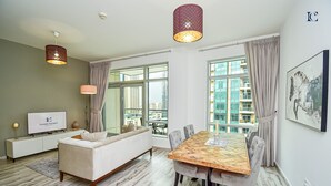 A modern living room with a sofa, dining table, and two pendant lights. - New 1BR Apt - Burj Khalifa View - LOFT (Dubai)