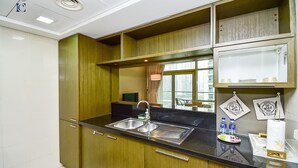 A modern kitchen with stainless steel appliances, wooden cabinets, and a black countertop. - New 1BR Apt - Burj Khalifa View - LOFT (Dubai)