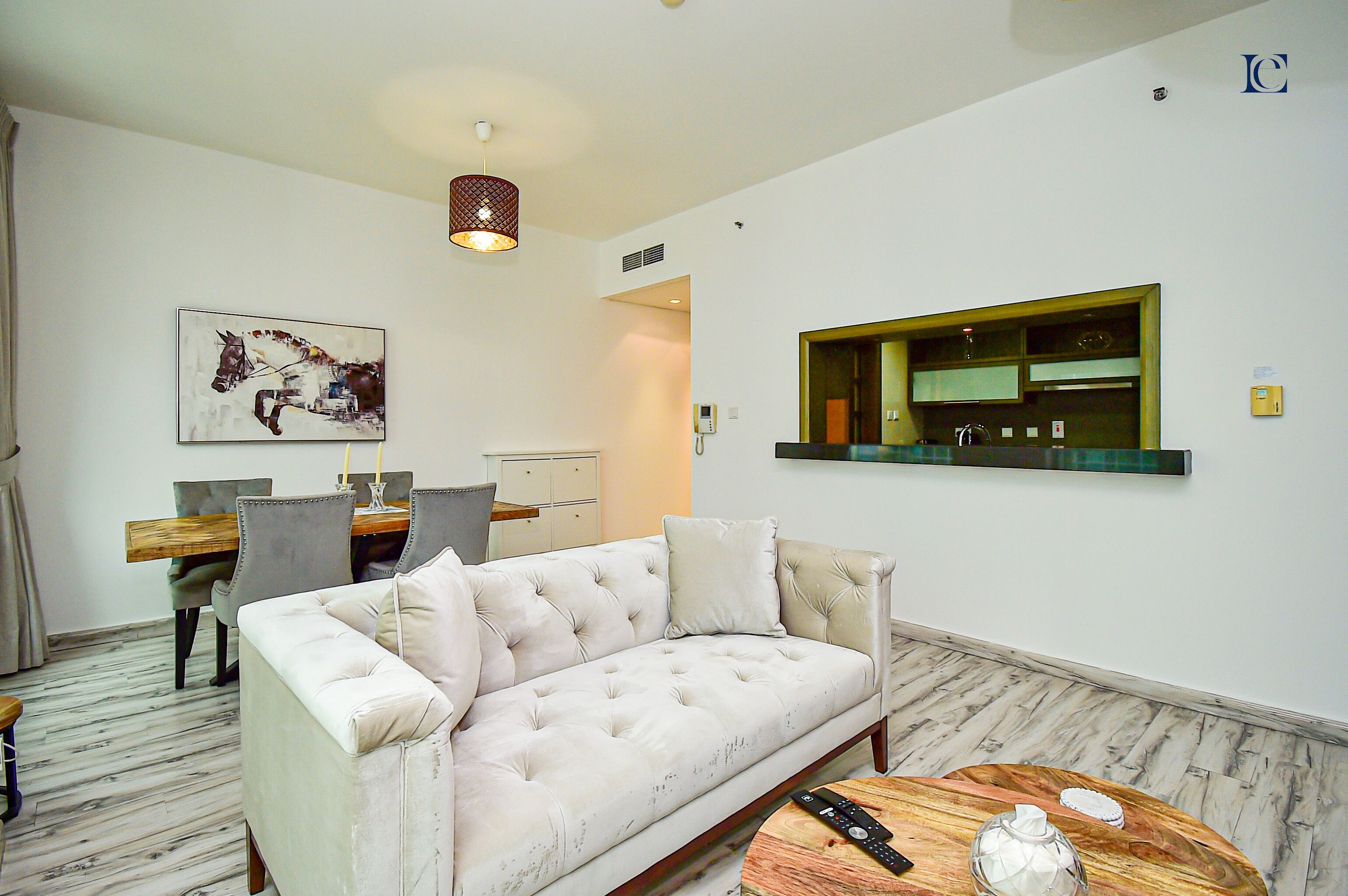Un salon moderne avec un canapé blanc, un coin repas avec une table et des chaises en bois, et une cuisine avec un plan de travail vert.