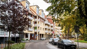 En flervåningsbyggnad med bostäder, balkonger, en parkeringsplats och en gata med bilar.