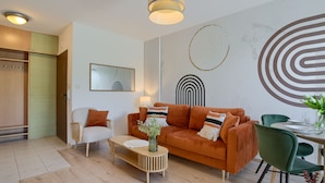 A modern living room with a sofa, armchairs, a coffee table, and a dining area with a table set for two.