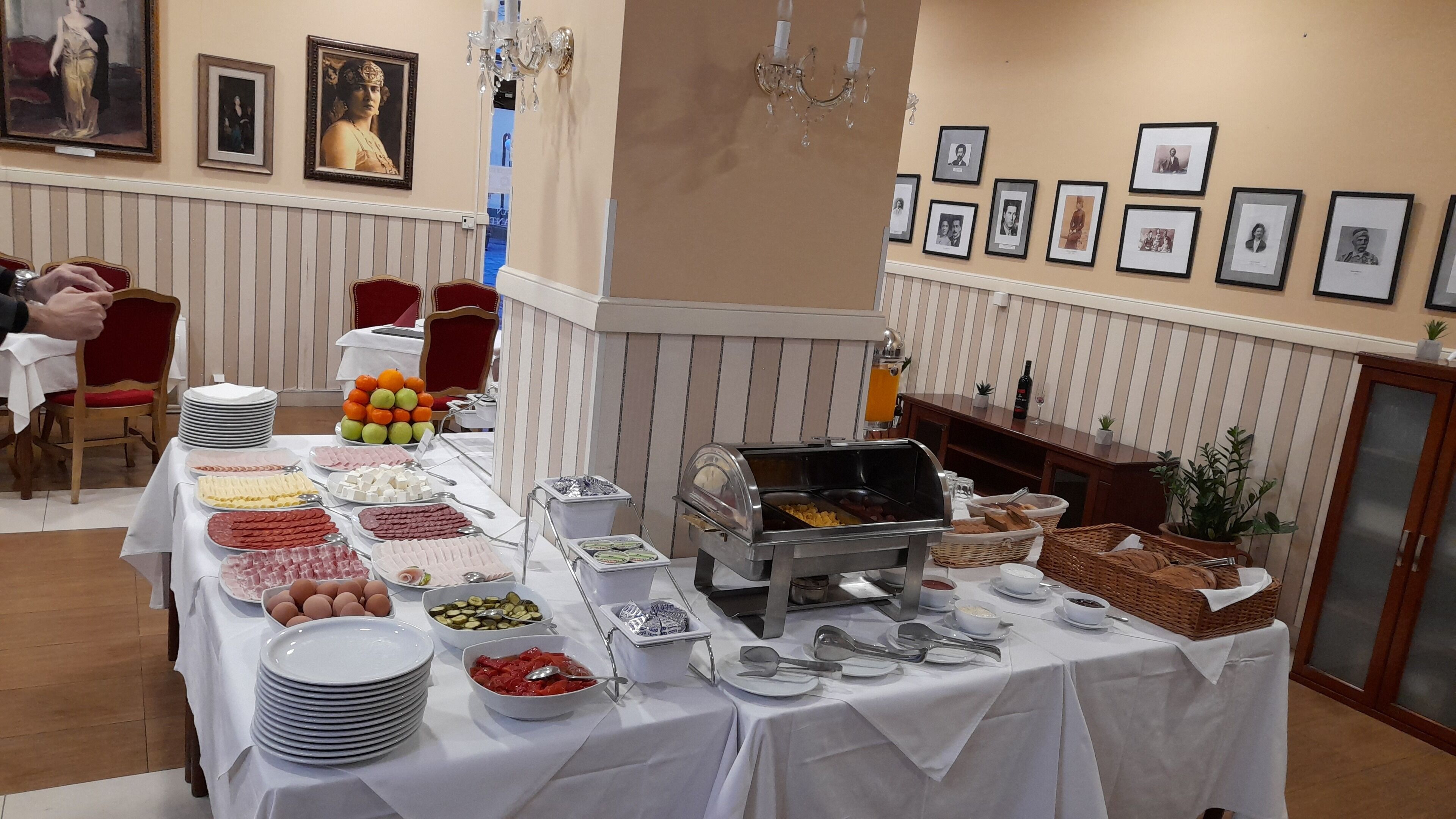 A buffet setup with various food items and a grill station, surrounded by framed pictures on the wall.