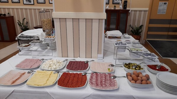 Una mesa de buffet con diversos alimentos, incluyendo carnes, quesos y huevos.