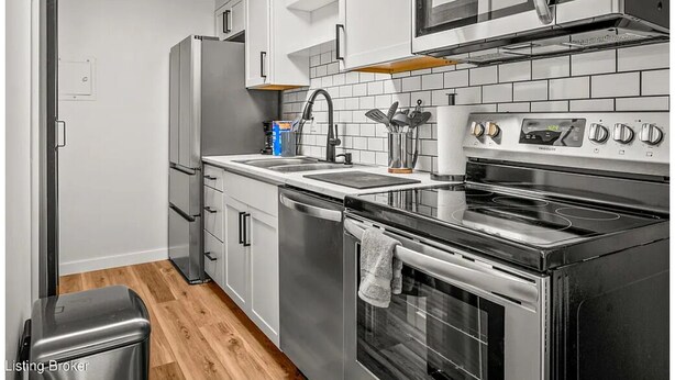 A compact kitchen with a stainless steel refrigerator, a microwave, a stove, and a dishwasher.