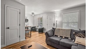 A modern living room with a grey sofa, a coffee table, and a dining area with a table and chairs.
