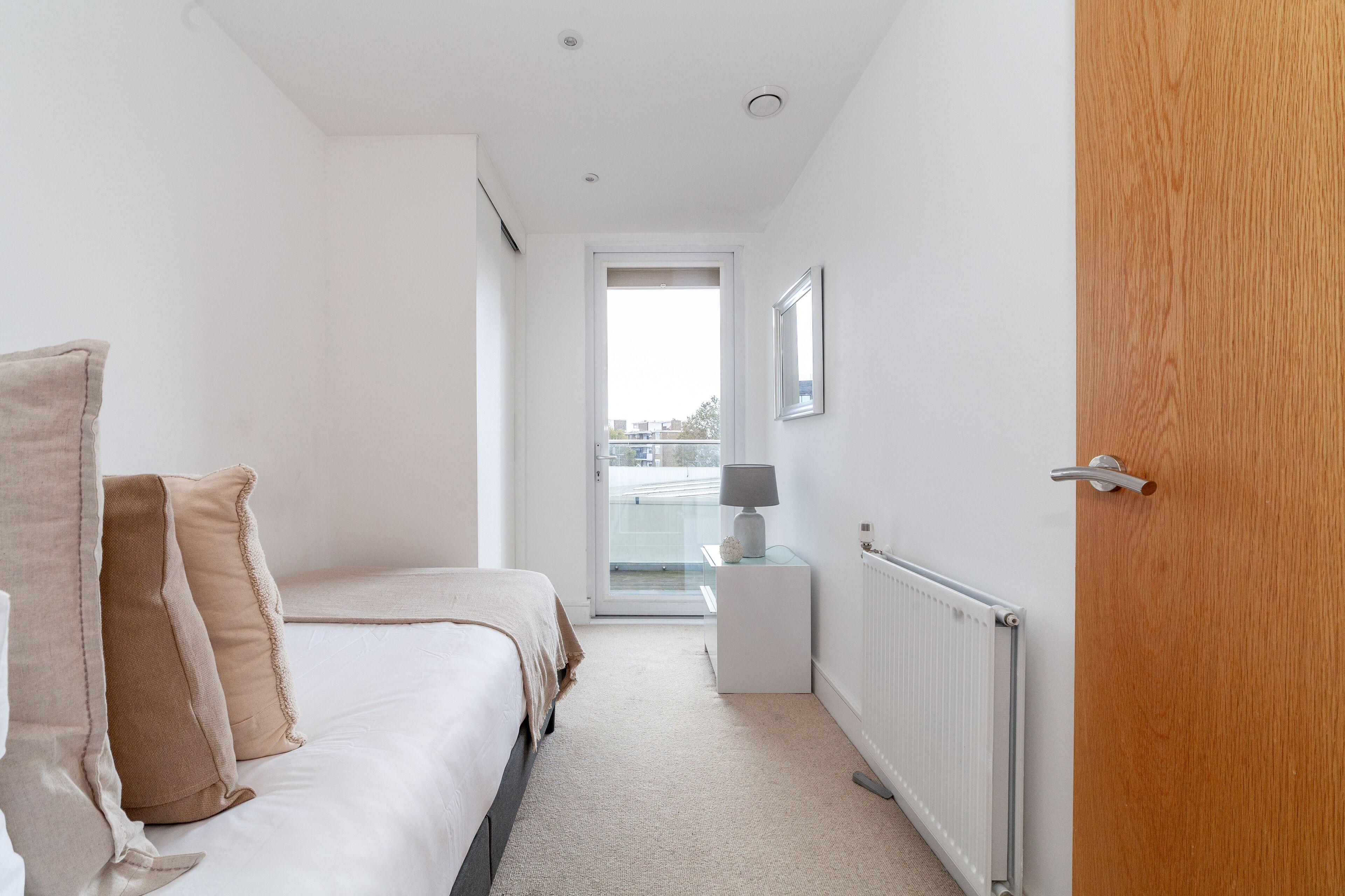 Un dormitorio con cama, mesita de noche y vistas a través de una puerta abierta.
