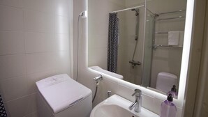 Ein Badezimmer mit einem weißen Waschbecken, einem Spiegel und einer Dusche mit Glastür.