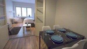 Ein moderner Essbereich mit einem Tisch für vier Personen, einer Couch und einem Fenster mit Jalousien.