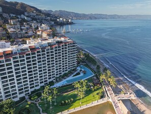 Ein Hochhaus-Hotel mit Pool, direkt am Strand und mit Blick auf das Gebirge.