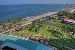 Ein Resort mit Pool, Palmen, Strand und einer Brücke.
