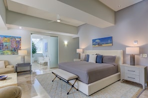 A bedroom with a large bed, bedside tables, a bench, a chair, and a painting on the wall. - Molino De Agua Beachfront 3-Bed Oasis w/ Pool, Spacious Balcony & Ocean Views (Puerto Vallarta)