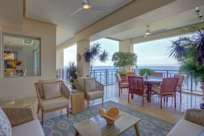 A spacious balcony with a view of the sea, furnished with chairs and a table, and decorated with potted plants. - Molino De Agua Beachfront 3-Bed Oasis w/ Pool, Spacious Balcony & Ocean Views (Puerto Vallarta)