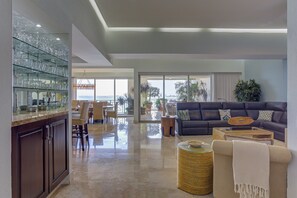 A spacious living area with a dark-colored sofa, a glass coffee table, and a wicker side table.