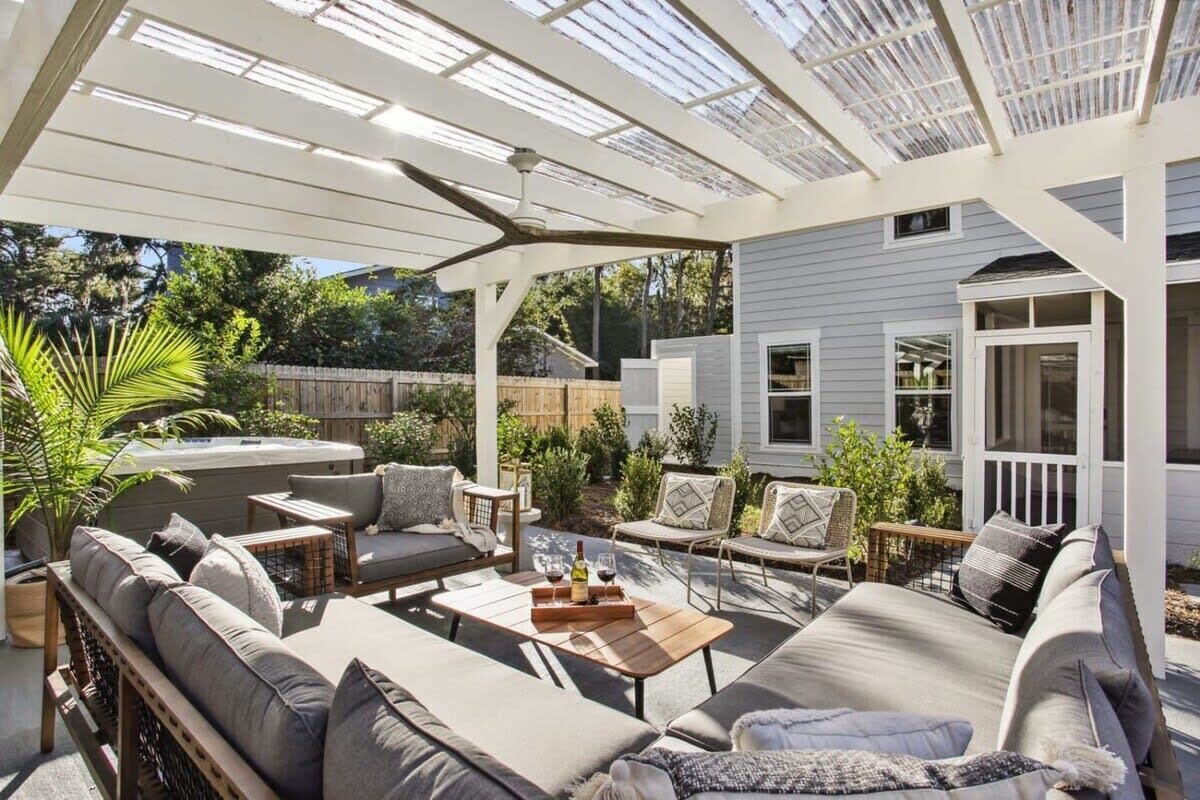 A covered patio area with a sofa set, a coffee table, and a dining table.