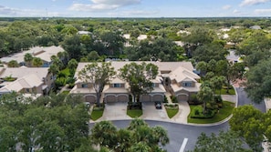 A residential area with multiple two-story houses, each featuring a central courtyard and a curved driveway. - Desired Pelican Landing First Floor Coach Home (Bonita Springs)