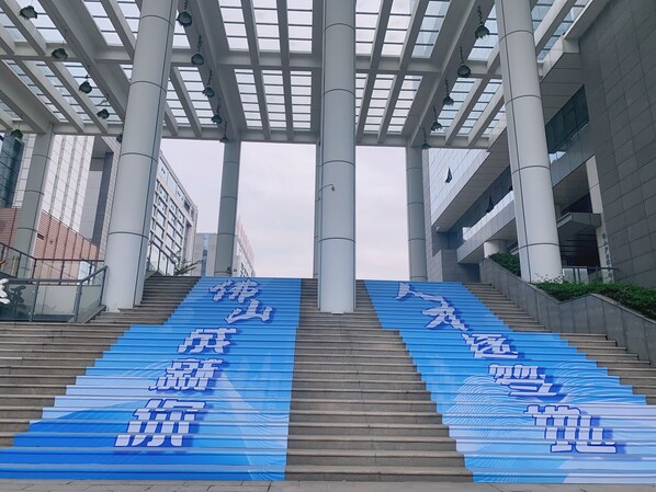 Una escalera conduce a un edificio con grandes lonas azules con texto blanco.