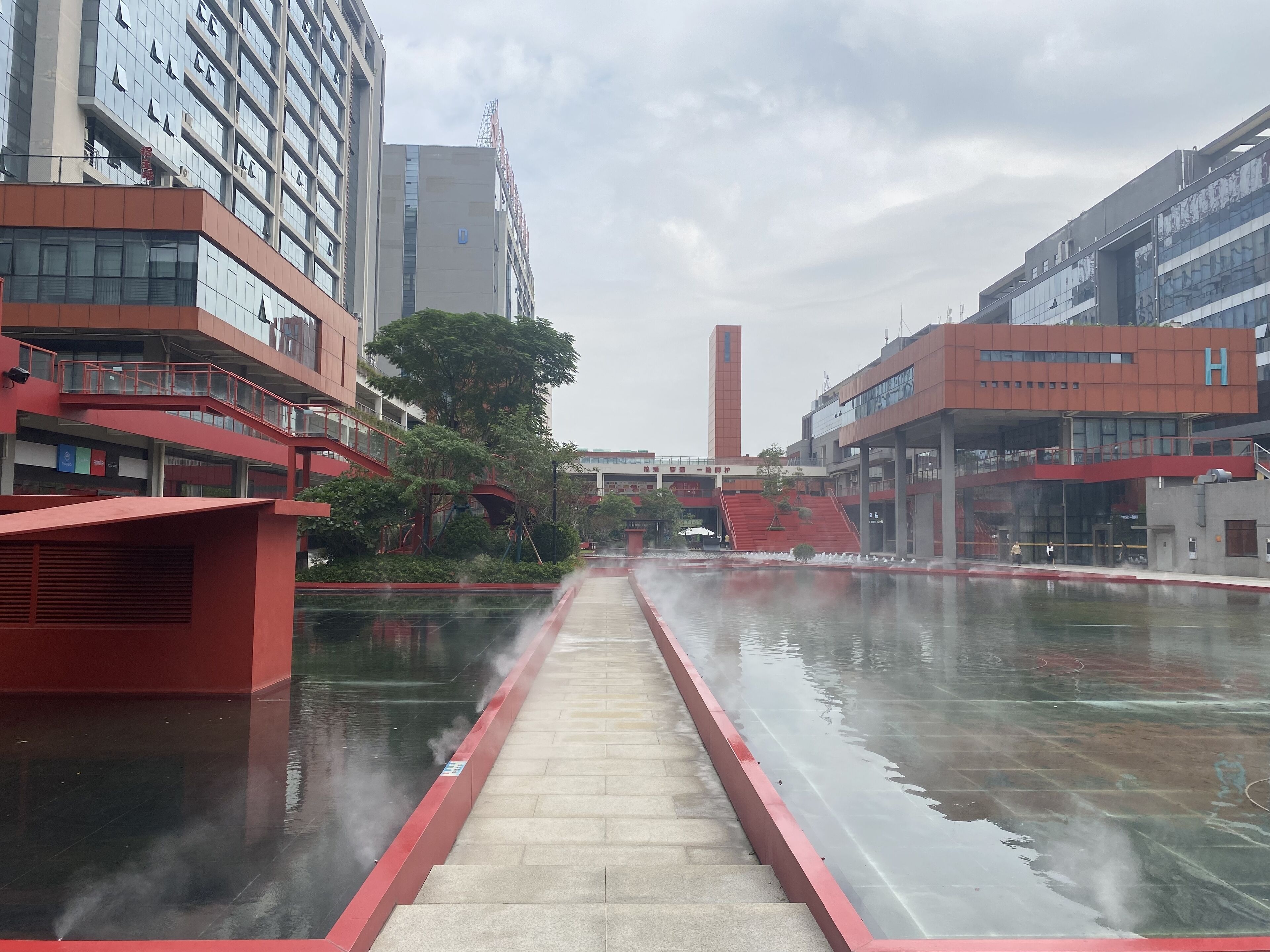 Un edificio moderno con un patio central que tiene una fuente de agua y un camino rojo.