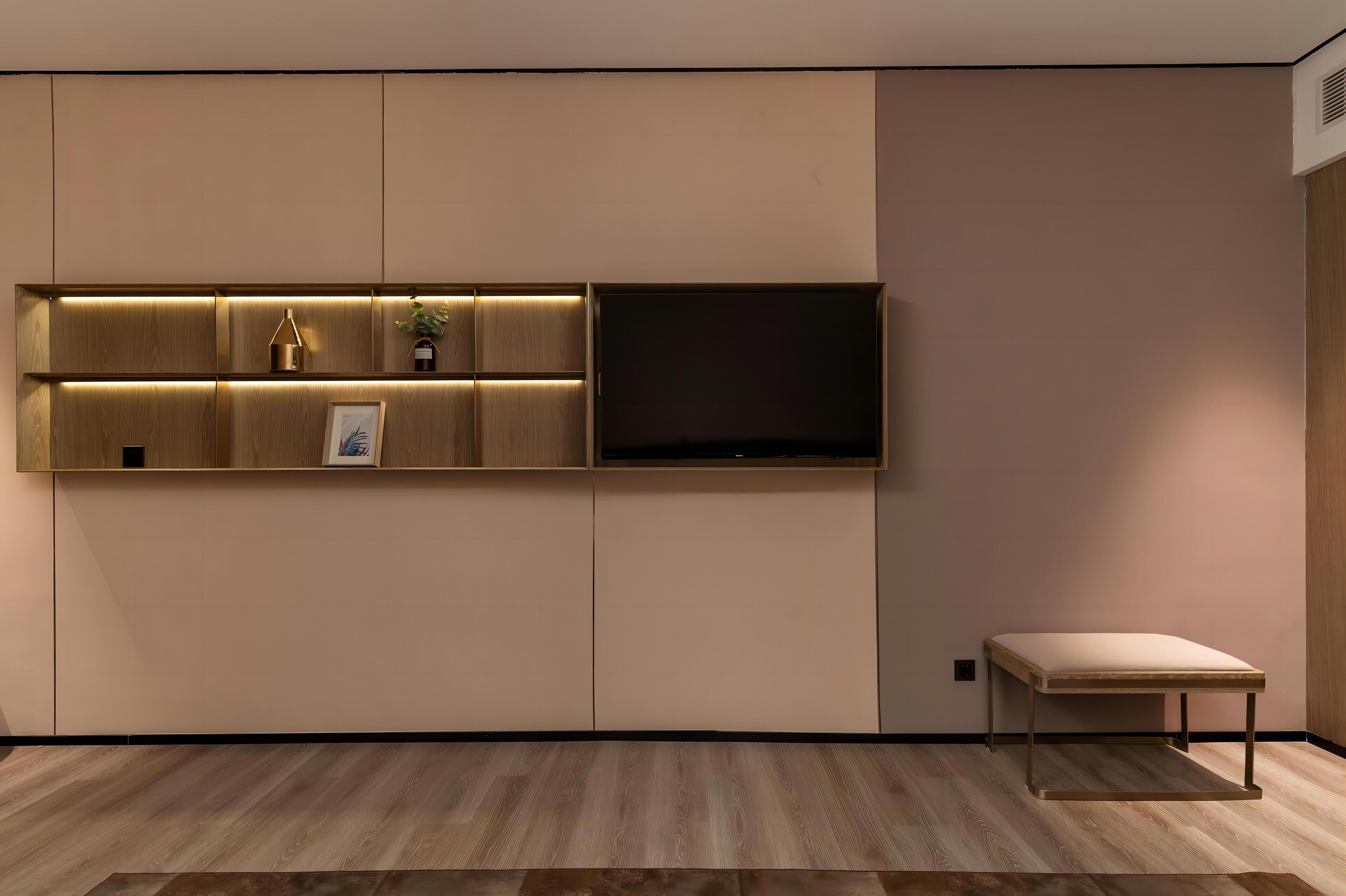 A modern room with a built-in TV shelf, a bench, and a wooden floor.