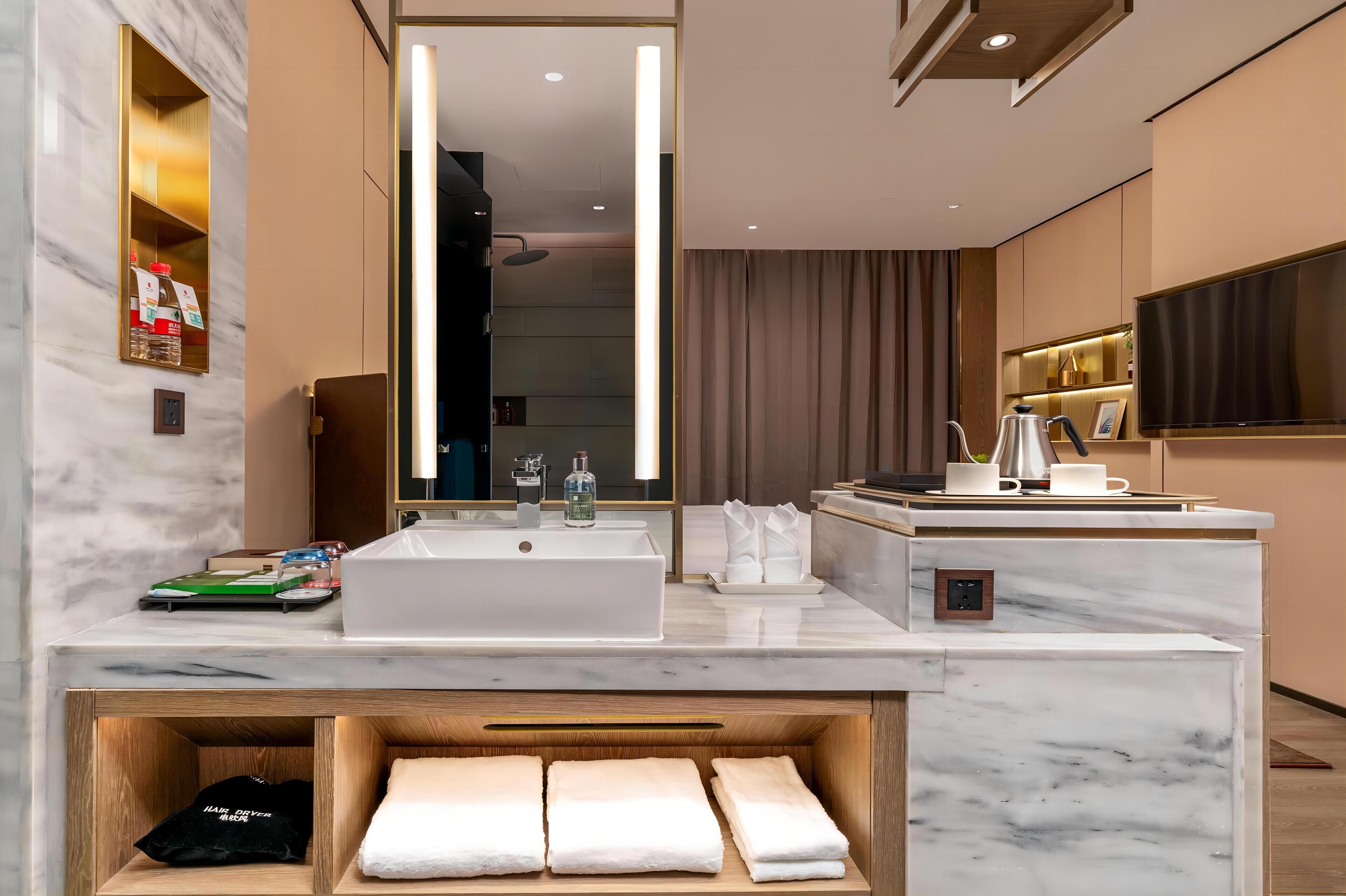 A modern bathroom with a large mirror, a white sink, and a vanity area.