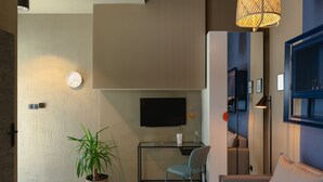 A modern living room with a sofa, a glass desk, a chair, a potted plant, a wall clock, and a television. - Lwowska City Garage (Warsaw)