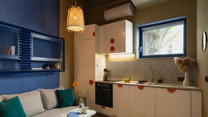 A compact kitchen with white cabinets, a built-in oven, and a window with a view of trees. - Lwowska City Garage (Warsaw)